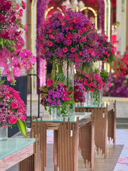 Corners comprising of bold hues and fragrant blooms. These tall glass vases filled with magenta and purple flowers line the walkway, adding to the overall magic of the venue. 💜🌺