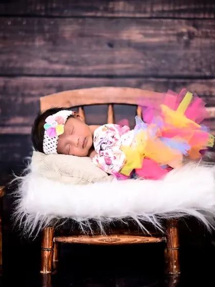 A newborn dreaming in a colorful tutu on a miniature wooden chair. This shot shows how I can incorporate vibrant colors even in a peaceful, sleeping pose.