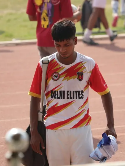 A player walking off the pitch after a hard-fought match, carrying his gear and the day's experience.