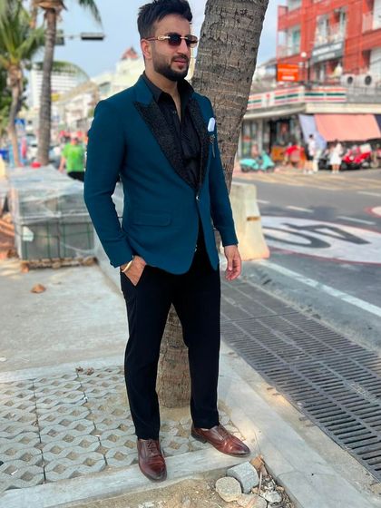 A client looking stylish in a teal blazer with a black textured lapel. This versatile piece is perfect for a destination wedding or a formal evening out.