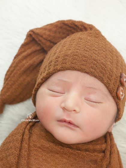 A macro shot of a sleeping baby in a textured brown bonnet. I love focusing on the delicate features like their eyelashes and the shape of their lips.