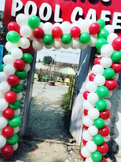 A classic red, white, and green balloon arch installed at the entrance of a pool cafe, perfect for creating a welcoming, festive look for Christmas.