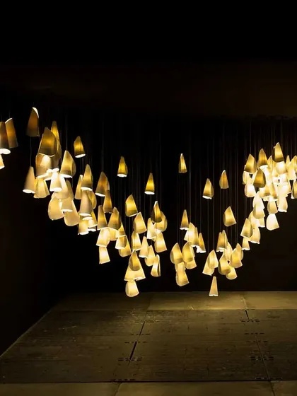 The Bocci 21 series arranged in a sweeping, horizontal curve. This demonstrates how these individual pendants can be composed to create large-scale, dramatic gestures of light in a space.
