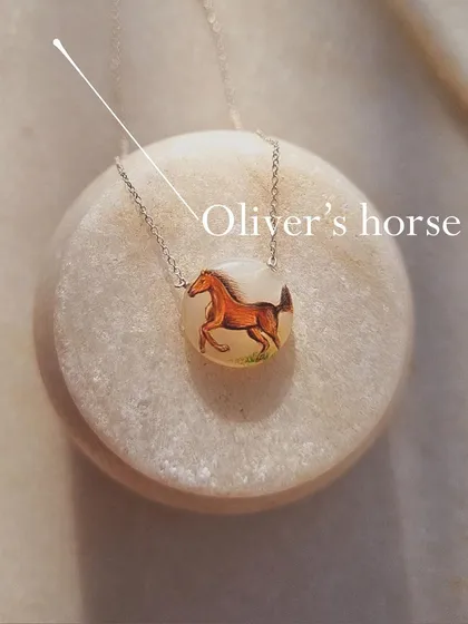 The "Oliver's Horse" pendant, a unique hand-painted talisman for emotional stability.