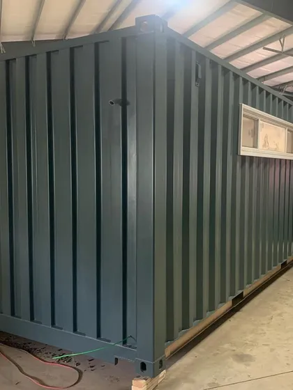 The exterior of the 20-foot container being converted into a music studio. Even in its early stages, the placement of windows and the solid structure demonstrate the potential for a highly functional and personalized creative space.