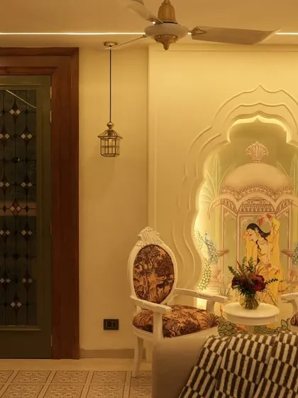An elegant seating nook featuring custom chairs with traditional motifs and a wall mural depicting a classic Indian scene. The intricate green doors add another layer of heritage-inspired design.