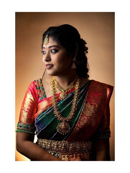 A stunning indoor portrait of the bride, Anitha, showcasing her intricate jewelry and beautiful silk saree.