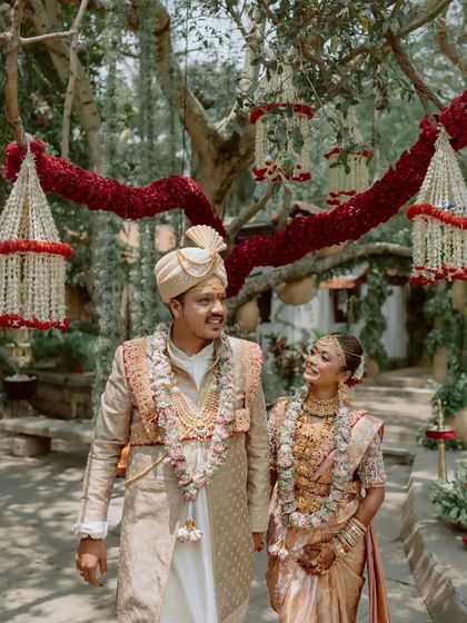 A couple walks through the gardens, framed by hanging floral decorations, a beautiful and romantic shot.