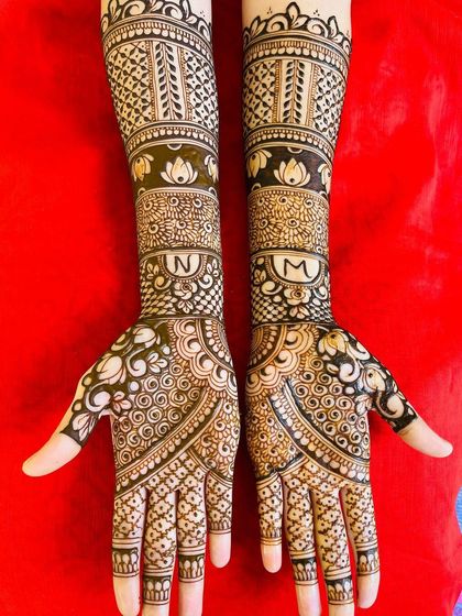 This design incorporates the initials 'N' and 'M' into decorative circles on the forearms, seamlessly blending them with the surrounding patterns.