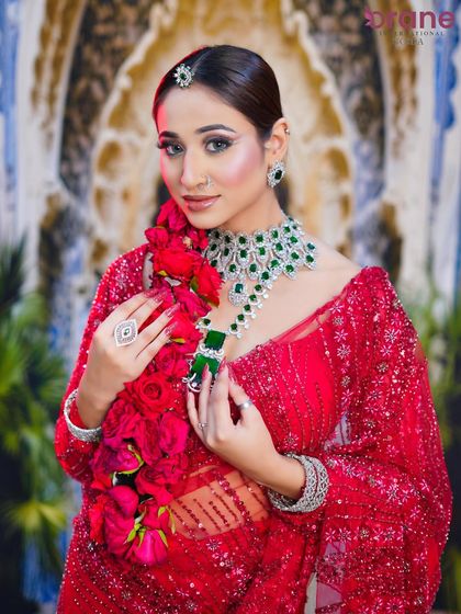 The bride's pose draws attention to the magnificent emerald necklace and the perfectly coordinated makeup.