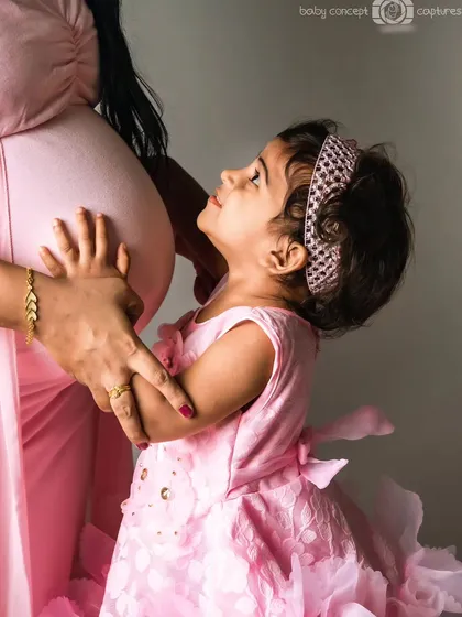 A heartwarming moment between a mother and her young daughter, who is looking up lovingly at the baby bump. This photo beautifully captures the anticipation and love of a big sister-to-be during a family maternity session.