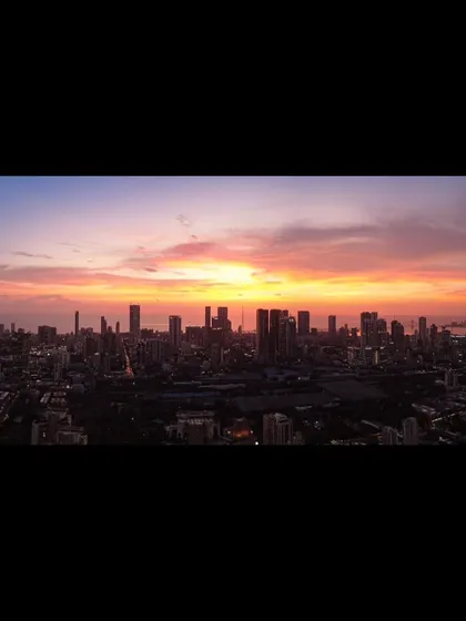 A letterboxed version of a panoramic Mumbai sunset, emphasizing the cinematic quality of the city's skyline against the colorful sky.