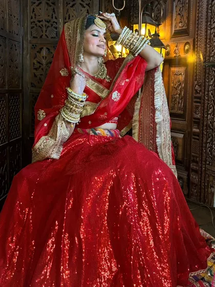For the classic bride, nothing beats a stunning red lehenga. I've paired this sequined outfit with a complete gold-toned bridal jewellery set, including a choker, maang tikka, and stacked bangles, to create a timeless and royal wedding look.