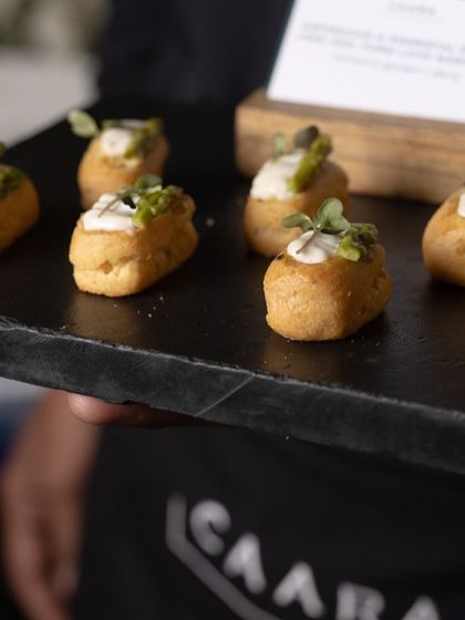 A server presenting a tray of our bite-sized appetizers at an event. These mini-quiches are filled with creamy toppings and fresh herbs, showcasing our commitment to quality and presentation in our pass-around service.