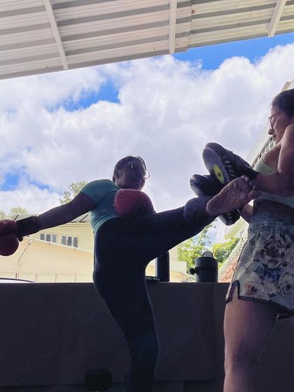 A high kick silhouetted against the sky in our open-air training area.