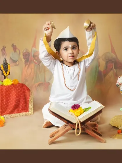 A young boy enthusiastically playing the cymbals, fully embracing his role as a little Varkari.