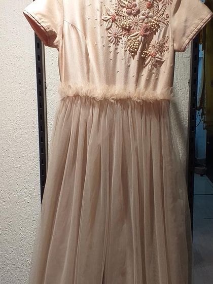 A delicate peach gown with 3D floral embroidery on the bodice and a soft tulle skirt. This dress is perfect for a daytime event, offering a soft and feminine look.