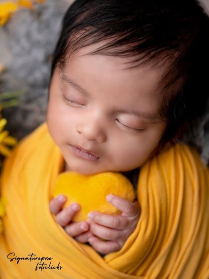 A newborn boy holding a yellow heart, a sweet and simple prop for our sunflower-themed shoot.