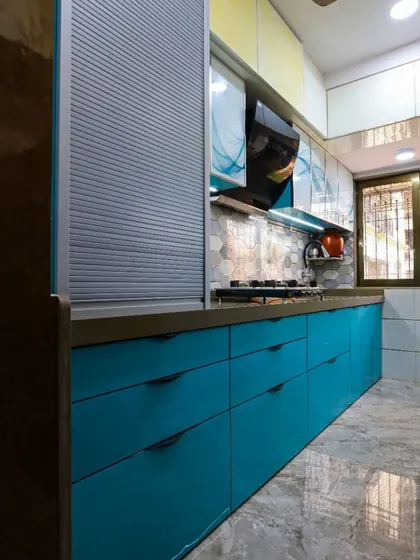 A vibrant modular kitchen with bold teal cabinets and a rolling shutter unit for appliances, combining color with functionality.