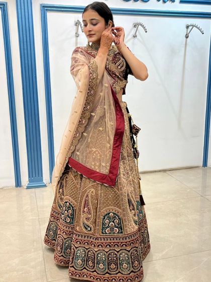 This elegant bridal lehenga features beautiful paisley motifs on a beige and maroon base.