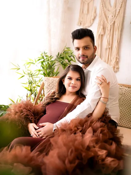A gorgeous portrait of an expecting couple in my cozy, boho-themed studio setup. The earthy tones of the dress and decor create a warm and inviting atmosphere.
