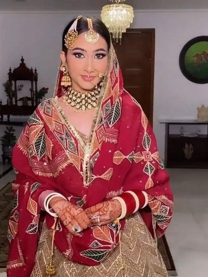 A Punjabi bride with a classic sleek bun covered by her phulkari dupatta. I ensure the bun is structured to support the dupatta and traditional hair accessories perfectly.