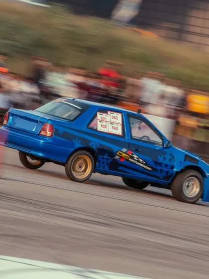 A blue modified sedan speeds down the track. We provide a platform for all types of cars, from home-built projects to professionally tuned machines.
