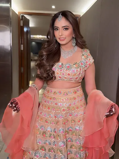 The complete sangeet look. The peachy tones in her makeup and the multi-colored embroidery on her lehenga create a beautiful, harmonious look.