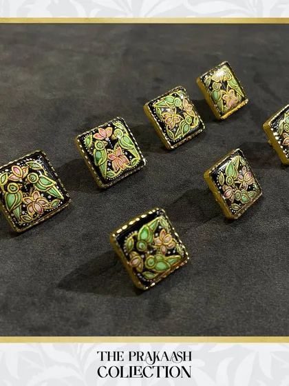 Our handmade metal buttons offer a unique upgrade for any garment. This set of square buttons features intricate floral meenakari work in pastel pink and green on a black enamel base, perfect for adding a touch of artistry to a blazer or kurta.
