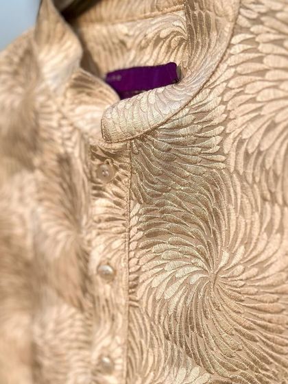 A close-up of a self-embroidered kurta. The intricate, swirling pattern adds a layer of texture and sophistication to this classic beige garment.