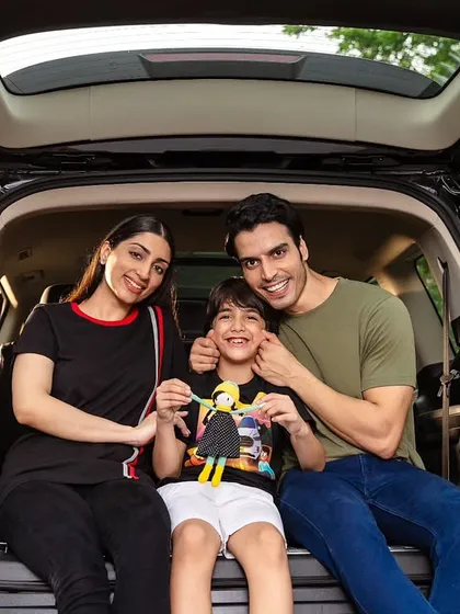 A classic family portrait set in the spacious trunk of an MG Motor vehicle. The direct smiles and comfortable posing create a welcoming and trustworthy image for the brand.