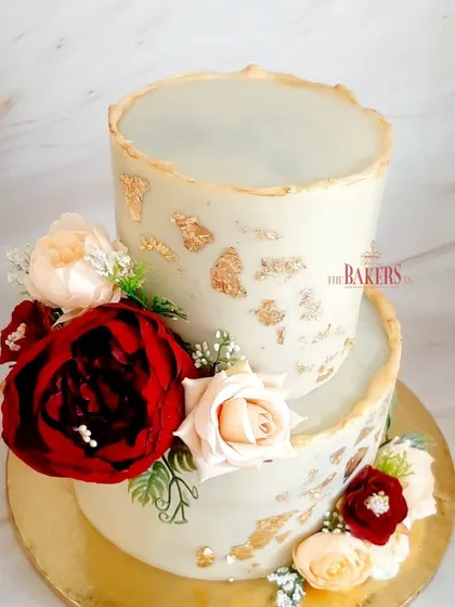 This rustic floral two-tier cake was designed for a beautiful engagement ceremony. It's a completely no-fondant cake, decorated with edible 24-carat gold leaf and a mix of red and blush silk flowers for a dramatic yet romantic look.