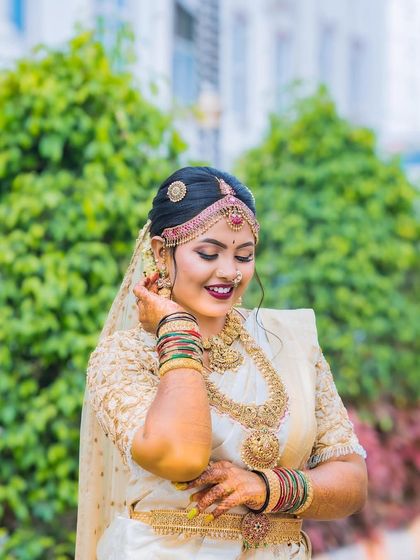 A smiling portrait showing my complete bridal look. The makeup features a bold berry lip and defined eyes, perfect for a classic South Indian wedding.