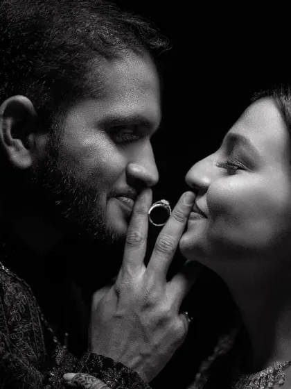 A playful and intimate black and white portrait. The couple's interaction with the ring adds a unique and personal touch to their engagement photo.