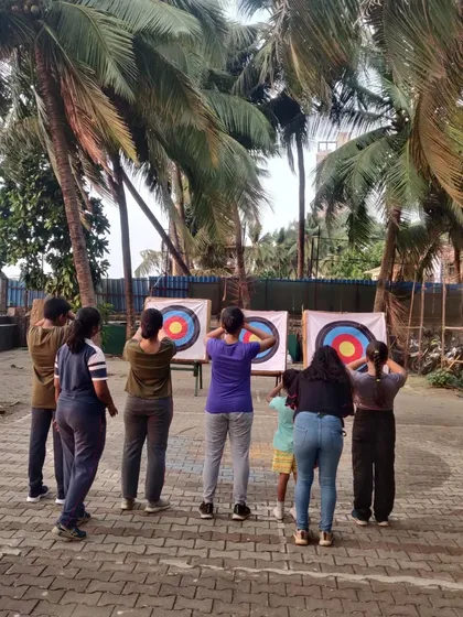 Students gather around the targets to check their scores and retrieve their arrows.