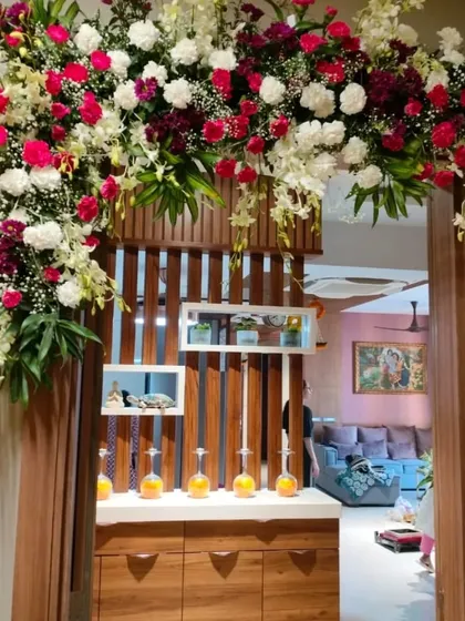 A sophisticated floral arch designed for a home's interior doorway. This arrangement features a rich mix of red, white, and burgundy roses, orchids, and carnations, creating a luxurious feel for the celebration inside.