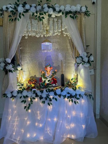 A pristine all-white mandap with a sheer, illuminated base and a small crystal chandelier. This design is the epitome of elegance and serenity.