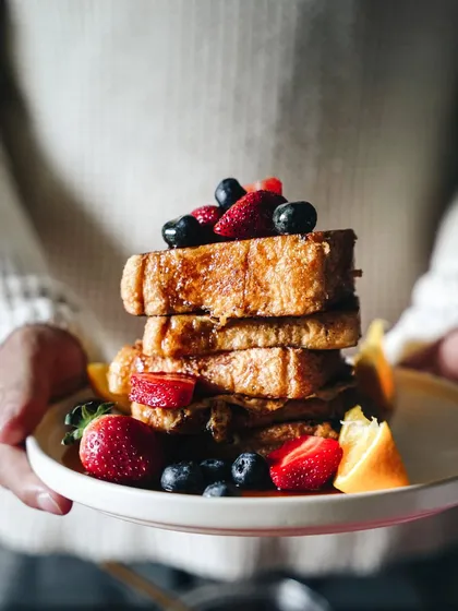 The last of a dreamy French toast series. This shot, with a person holding the plate, adds a human element and makes the breakfast stack feel warm and inviting.