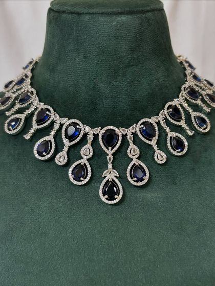 A close-up of the American diamond necklace with deep blue stones. This rental piece offers a dramatic and elegant look.