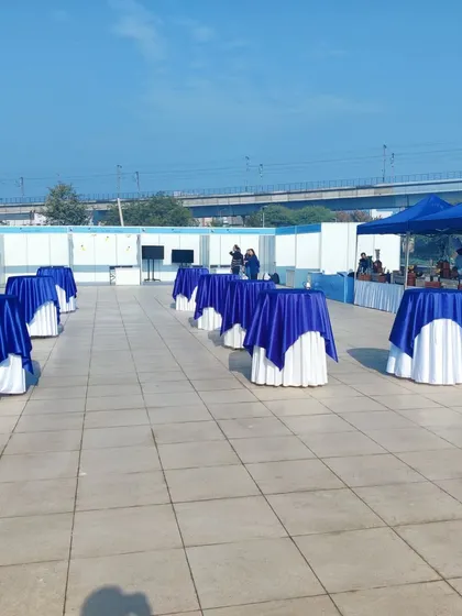 Cocktail tables draped in the client's brand colors, blue and white, are set up on the terrace. This arrangement provides space for networking and casual conversation during the corporate gathering.