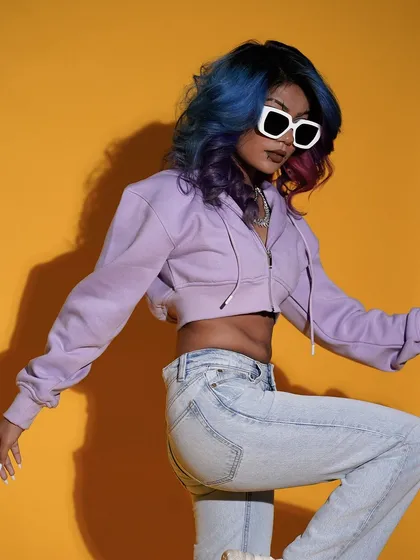 A dynamic pose against the yellow background, capturing the model in motion. This shot highlights her colorful hair and casual outfit, creating an energetic and youthful fashion photo.