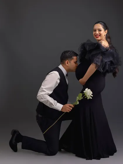 A classic and chivalrous pose with the father-to-be kneeling to kiss the baby bump, showing love and reverence for both mom and baby.