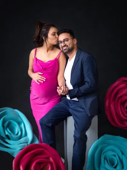 A sweet kiss on the cheek, surrounded by colorful props. This studio setup is perfect for a fun and vibrant maternity session.