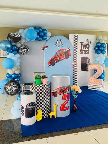 A 'Two Fast' race car theme for a 2nd birthday. The checkered flag details, tire props, and blue balloon arch create an exciting track-side vibe.