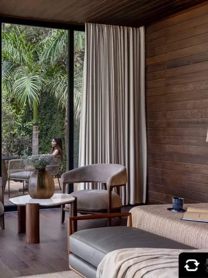 This bedroom offers a tranquil retreat with floor-to-ceiling windows that open onto a private deck. The wood-paneled walls and soft furnishings create a warm, cabin-like feel connected to the outdoors.
