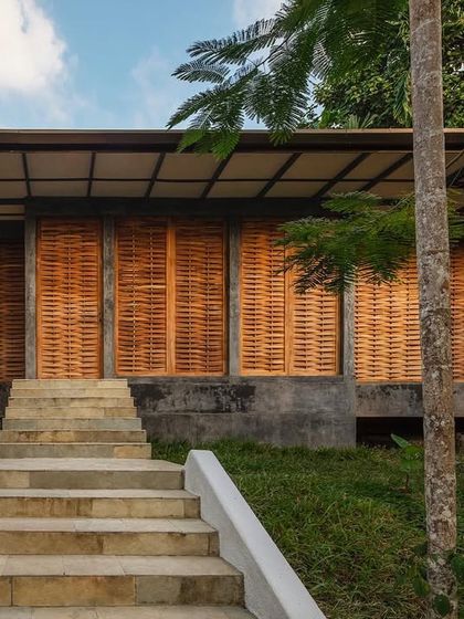 The exterior of the private villa, showing how the entire structure is enveloped by pivoting woven teak panels. This creates a breathable skin that responds to the tropical climate.