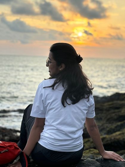 A trekker looking out at the sunset over the ocean in Gokarna.