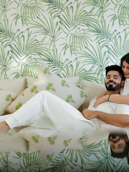 A cozy and intimate moment at home. This relaxed shot on the couch, with the couple in matching white outfits, captures the simple, everyday love that is the foundation of every great love story.