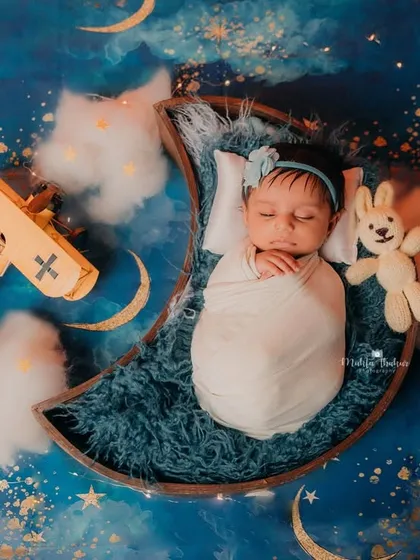Flying through a starry night sky. The little airplane prop adds a touch of adventure to this dreamy moon and stars newborn photoshoot.