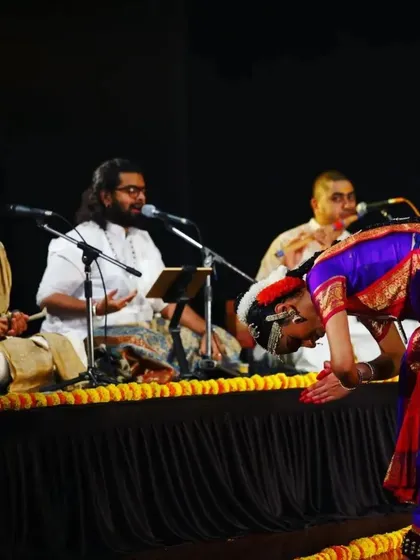 A dancer shows reverence to the musicians who provide the soul of the performance. This moment from Sahana's Arangetram highlights the deep respect inherent in our tradition.
